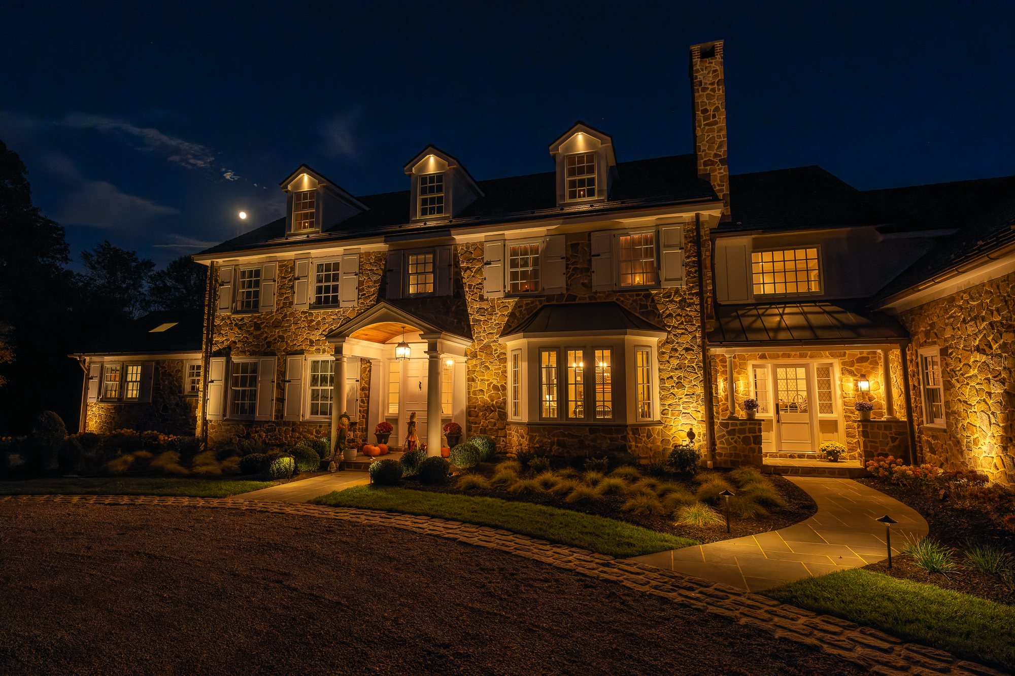 Stone manor facade with architectural uplighting at night — landscape lighting serving Newtown Square, PA